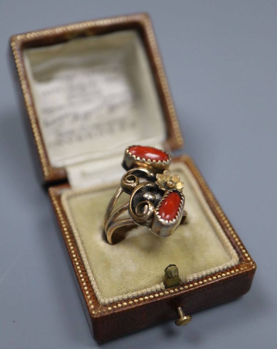 An early 20th century Arts & Crafts yellow and white metal and two stone cabochon coral set triple shank dress ring, size O,